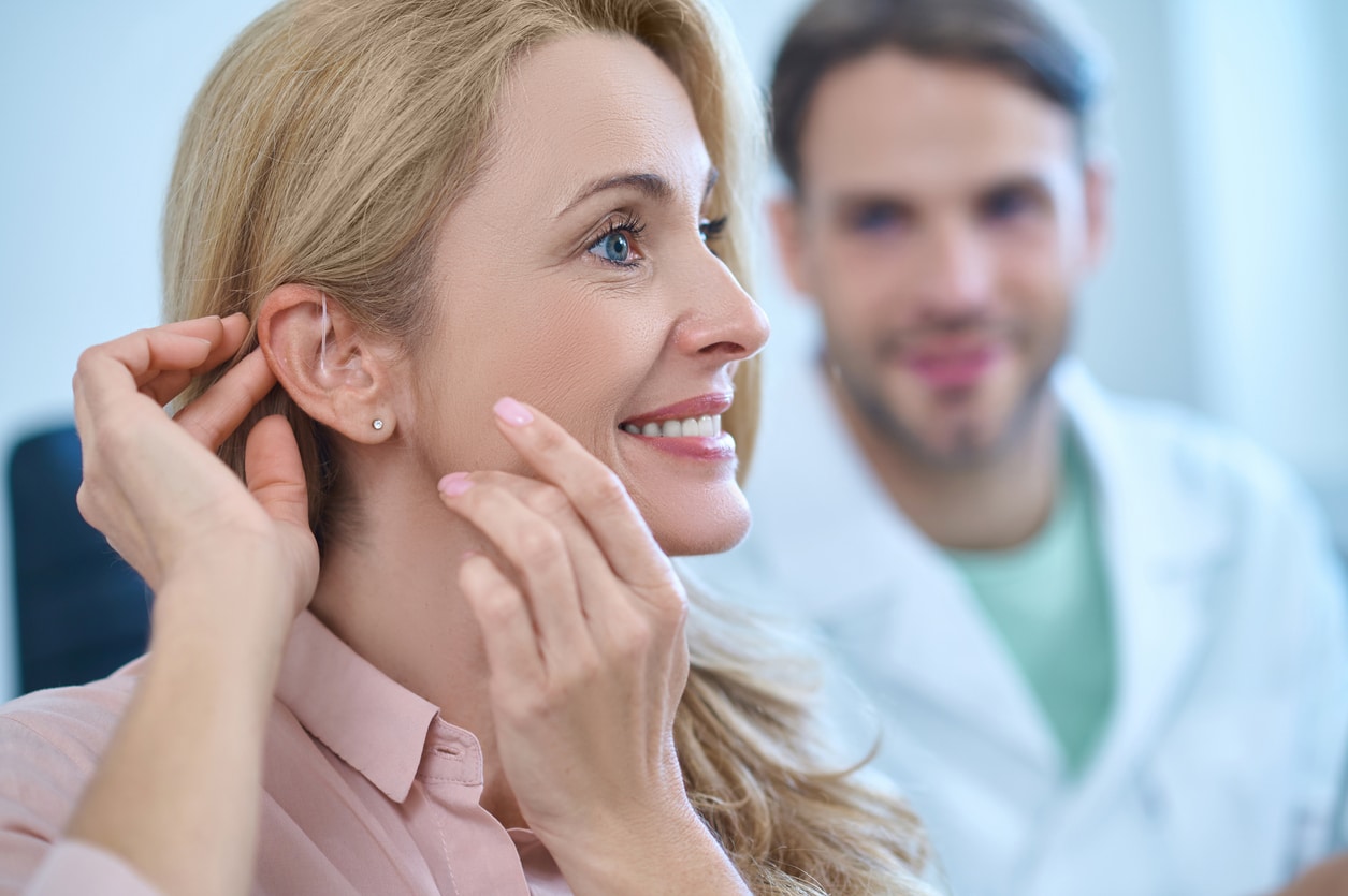 Happy woman looking at her new hearing aid