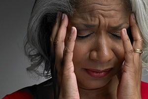 woman holds her head in her hands in pain